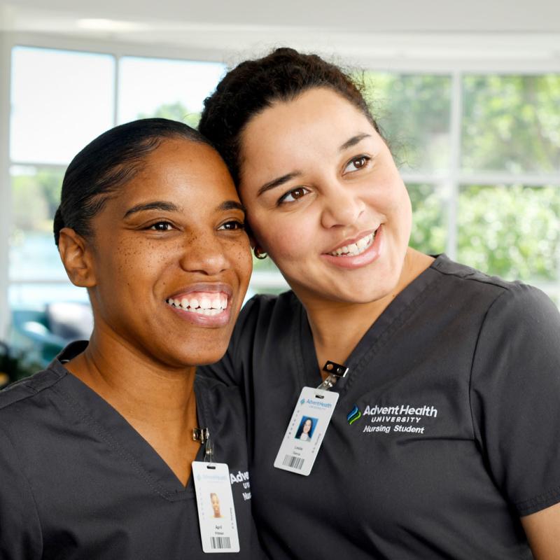 Two female nursing students putting their arms around each other and smiling