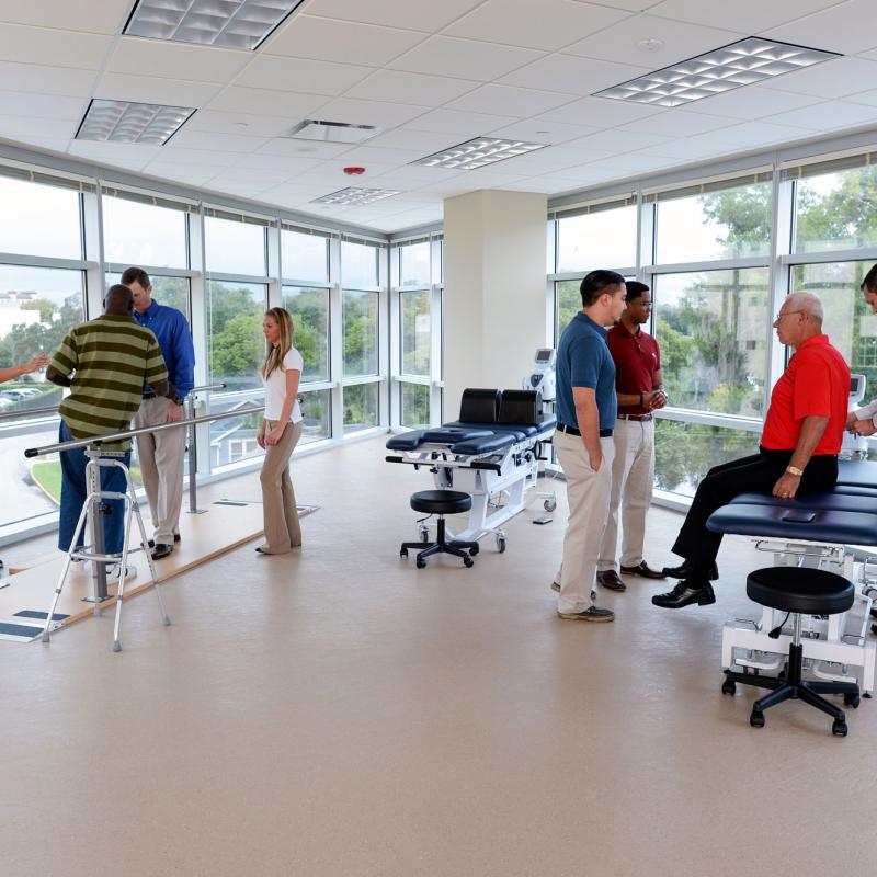 Two faculty members teaching separate groups of students physical therapy skills.
