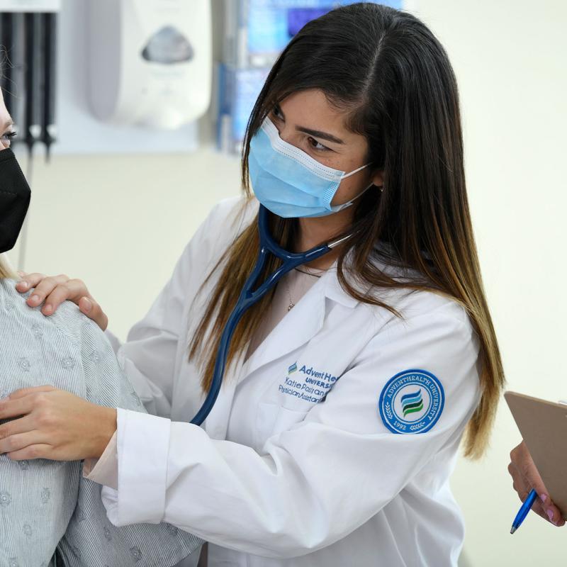 A female physician assistant student using a stethoscope on a patient