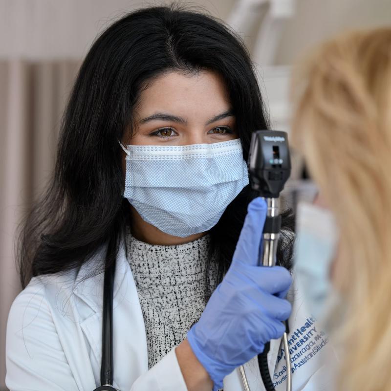 A female PA student in the lab conducting an eye exam on a patient