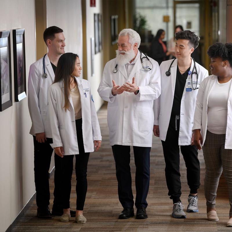 Physician assistant students walk down the hall with a faculty member