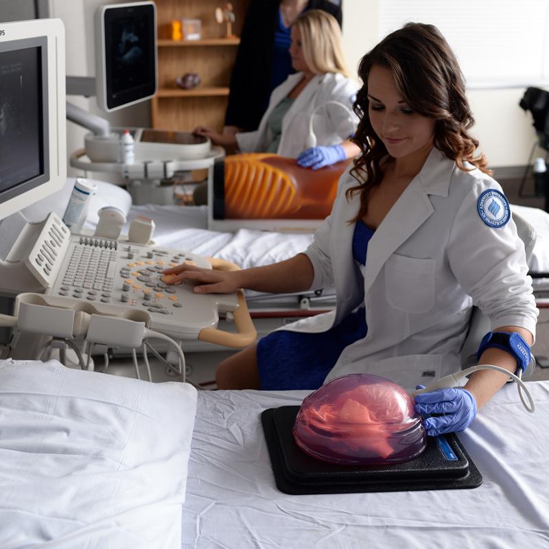 A female sonography student scanning a cardiovascular phantom
