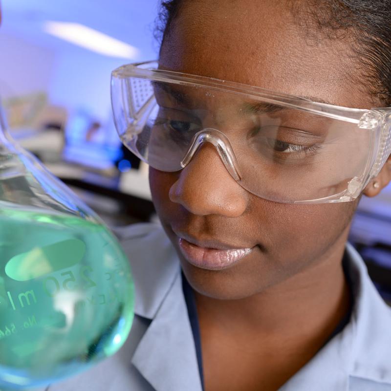 A female student observes a beaker in the chemistry lab