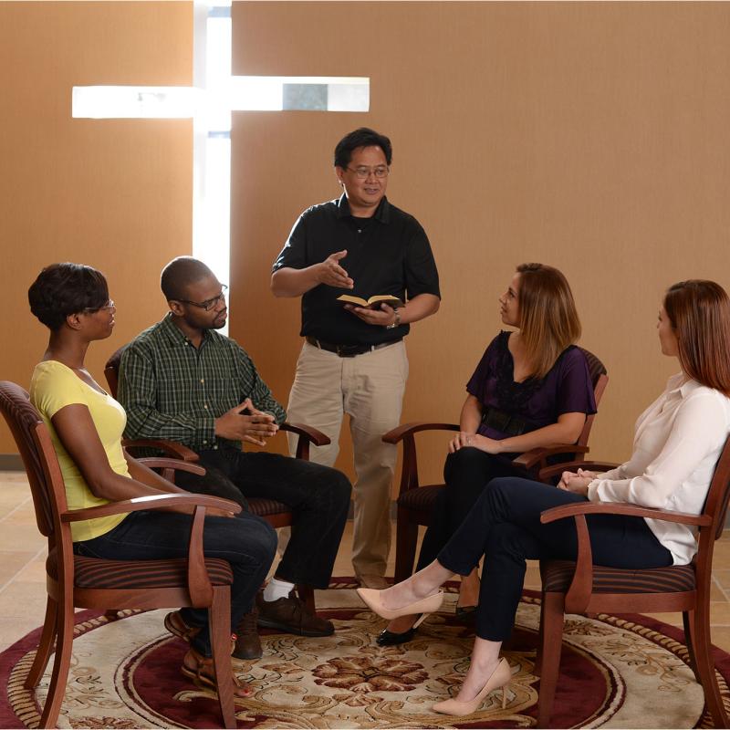 A group of students participating in bible study with a staff member in the chapel