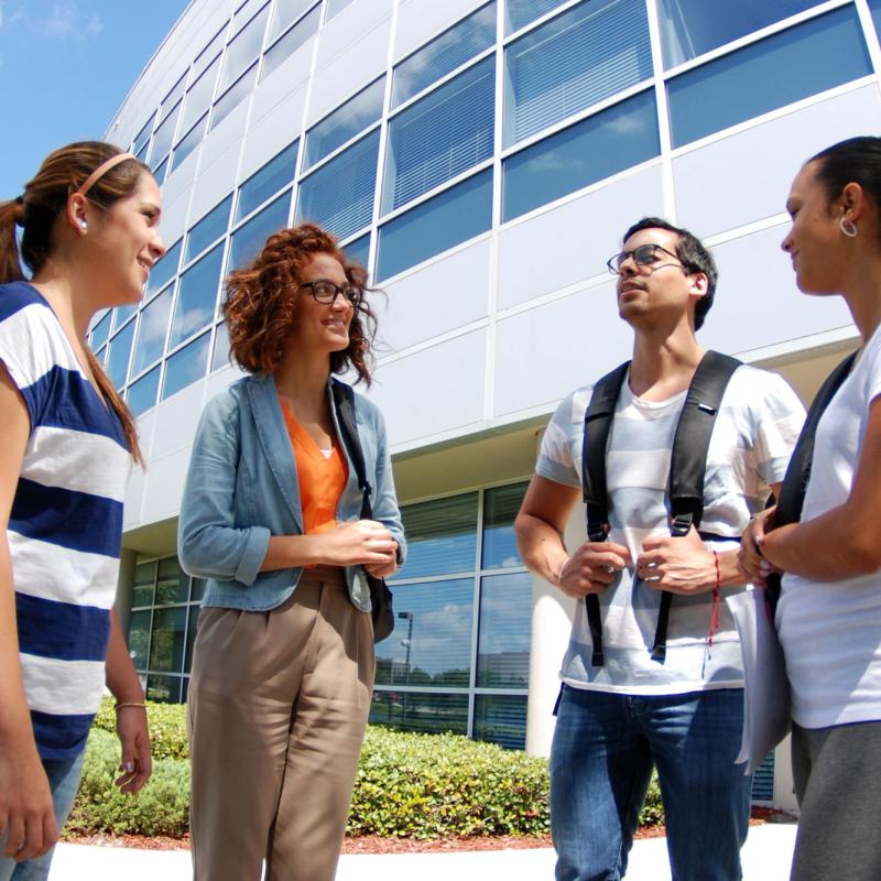 A group of students conversing outside of AHU's Campus Center building