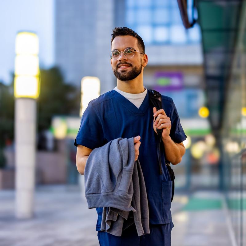 A male travel nurse standing outside a buidling