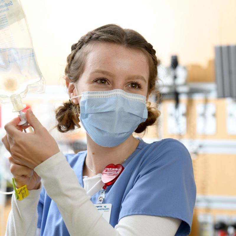 A young, female nurse sets up a patient's IV