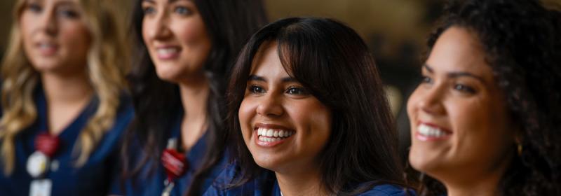 four smiling students in classroom on campus