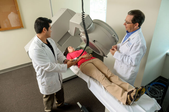A nuclear medicine student performing a scan under faculty supervision