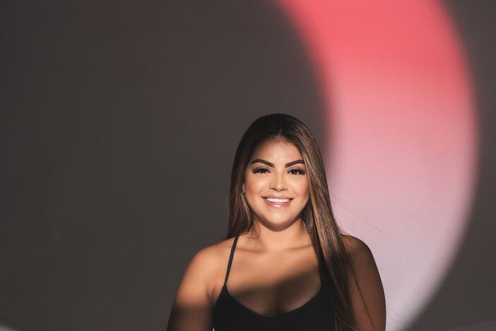 Portrait of a smiling woman in black sportswear under artistic lighting indoors.
