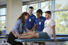 Physical Therapy students and professor examining a patient's leg