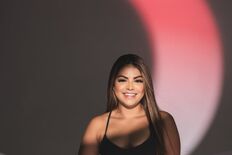Portrait of a smiling woman in black sportswear under artistic lighting indoors.