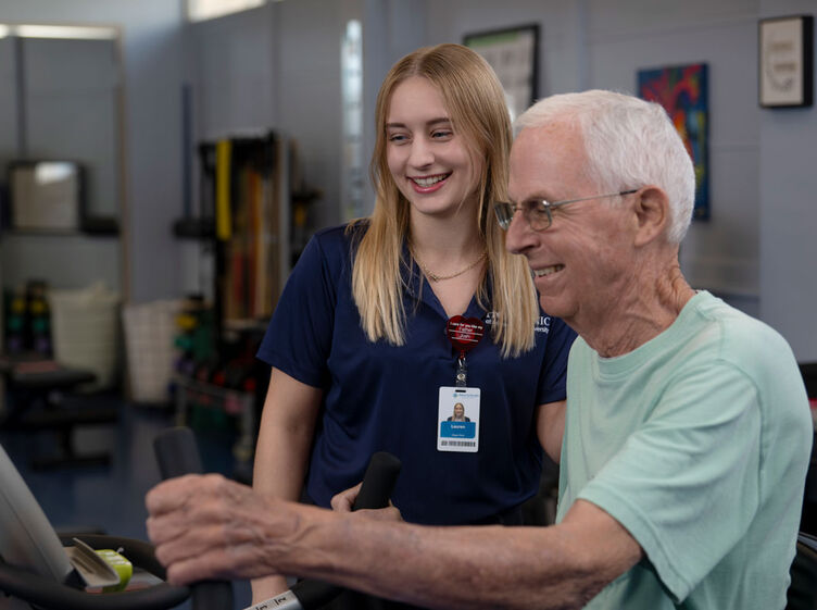 image of occupational therapy assistant student assisting geriatric patient on exercise machine