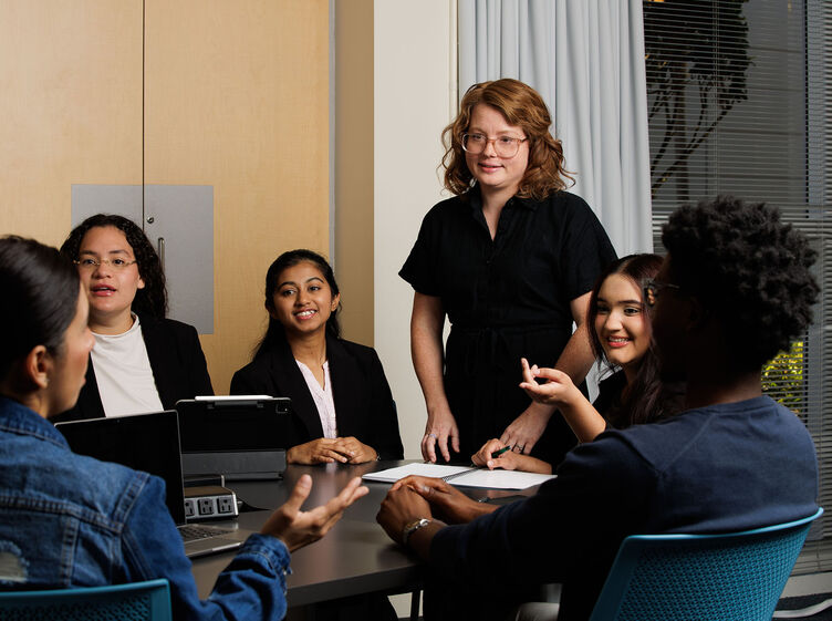 A teacher lectures to a small group of students in a conference room
