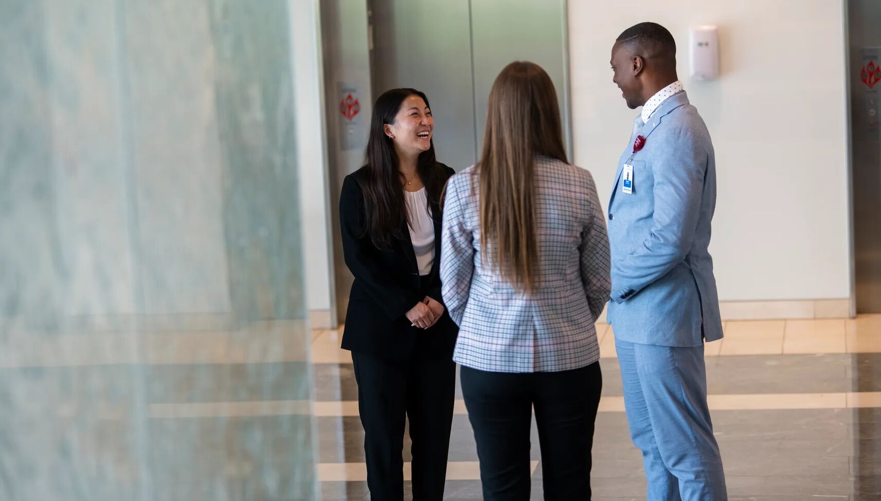 three adventhealth employees smiling and talking in hallway of hospital