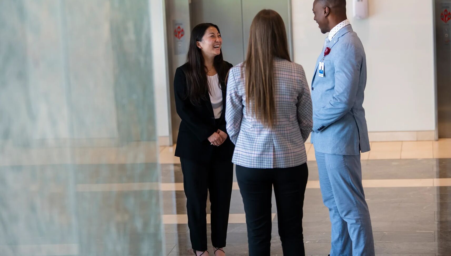 three adventhealth employees smiling and talking in hallway of hospital