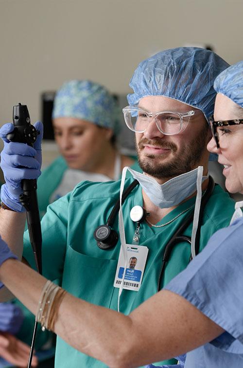 A male nurse anesthesia student using equipment with the help of a faculty member