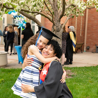 A graduate and her daughter hugging after graduation ceremony.