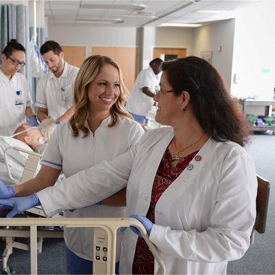 Students practicing in the nursing lab under the supervision of a faculty member