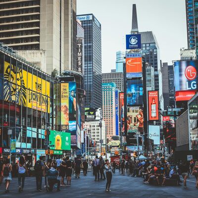 Bustling daytime view of Times Square with crowds, skyscrapers, and iconic billboards in New York City.