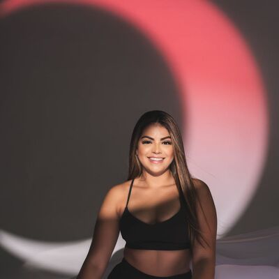 Portrait of a smiling woman in black sportswear under artistic lighting indoors.
