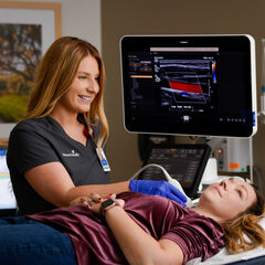 A sonographer scans a patient