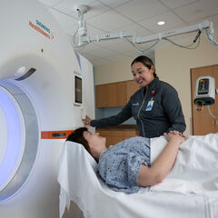 An MRI tech smiles at a patient prior to performing a scan
