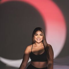 Portrait of a smiling woman in black sportswear under artistic lighting indoors.