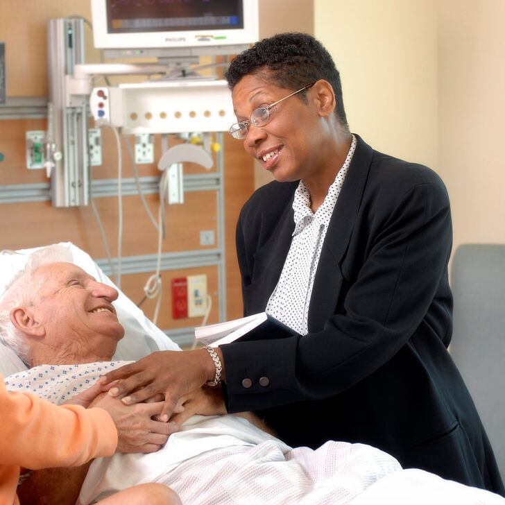 A hospital chaplain meets with a patient and family member