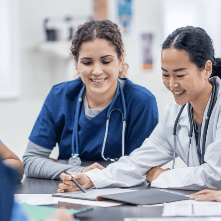 A group of nurses reviews documents at a table