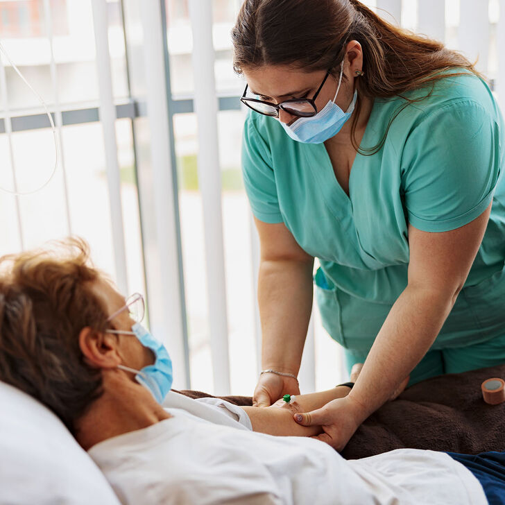 A registered nurse places an IV drip on a patient