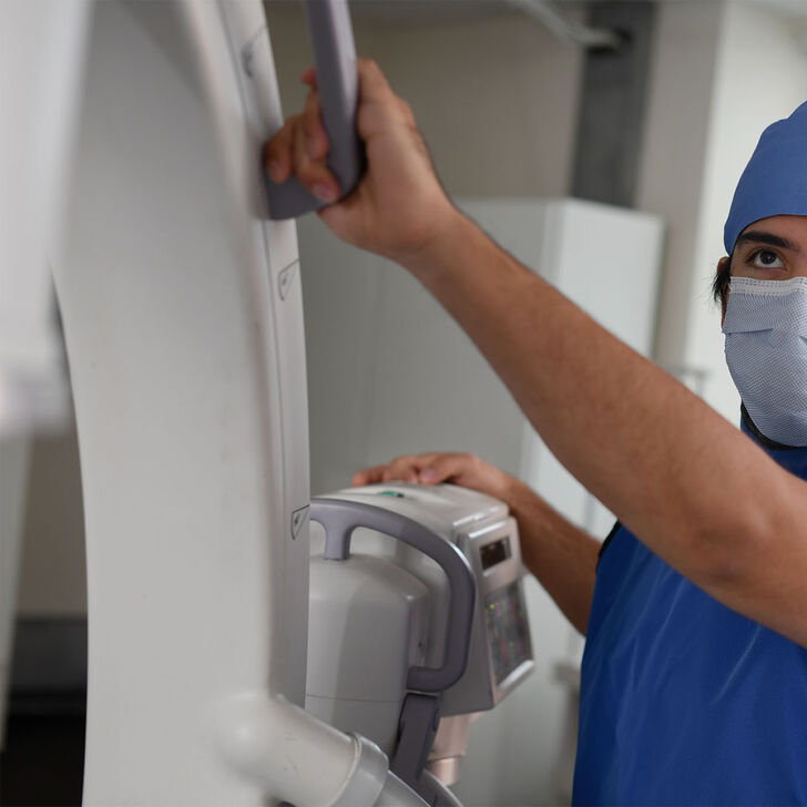 A radiography student positioning the arm of an x-ray machine