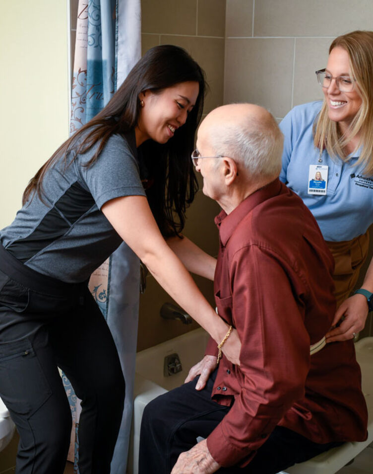 Image of faculty member smiling and helping patient with a student