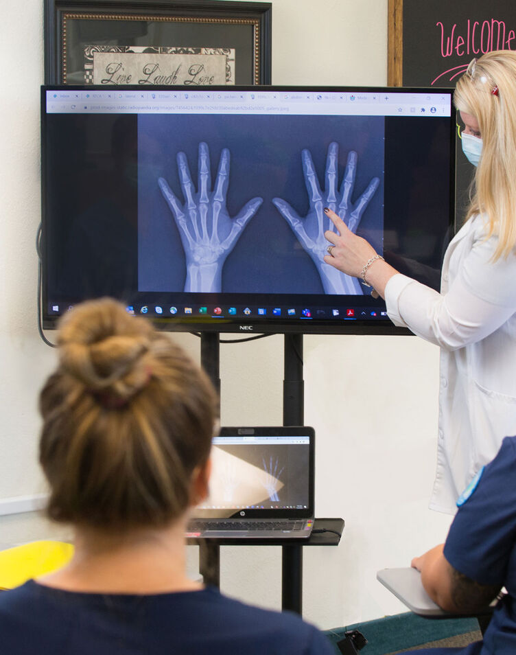 A radiography instructors showing students and x-ray of the hand