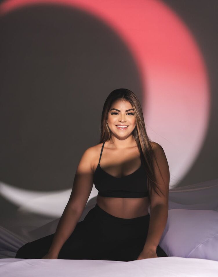 Portrait of a smiling woman in black sportswear under artistic lighting indoors.